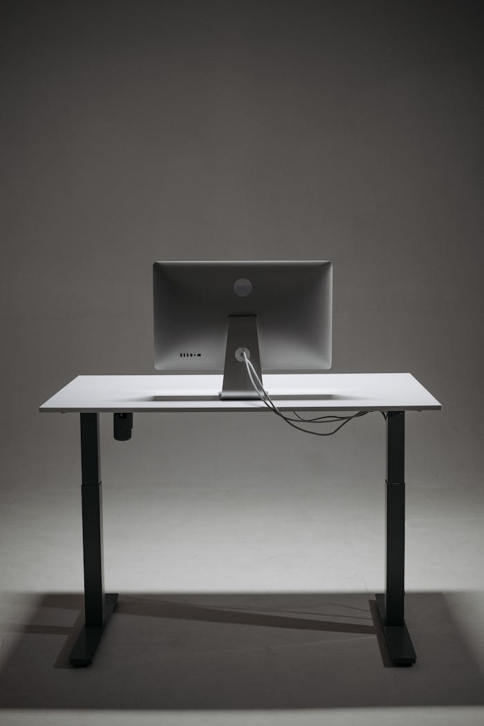 A sleek, height-adjustable standing desk featuring a modern monitor setup.